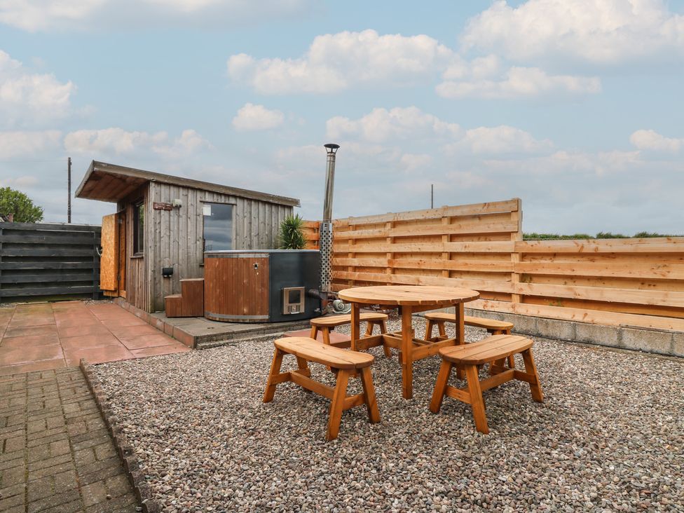 An outdoor area with a wooden cabin and seating at Rowan Cottage Redcastle near Arbroath