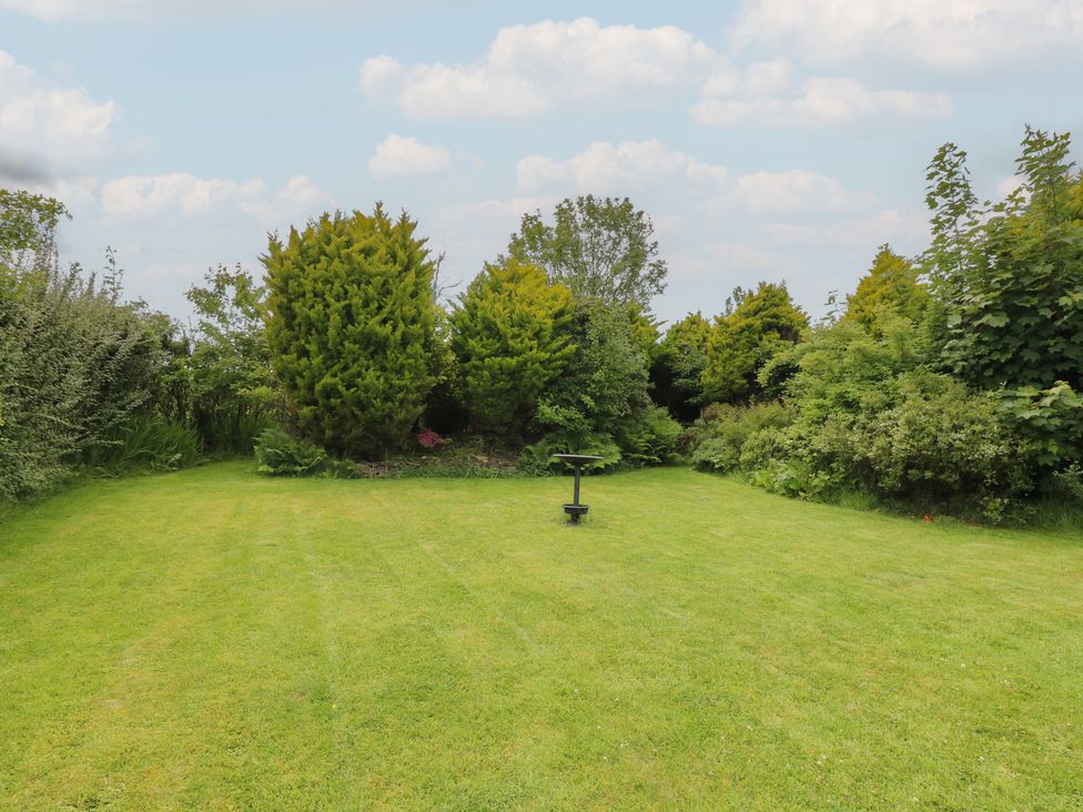 A garden with grass and trees at Rowan Cottage in Redcastle near Arbroath