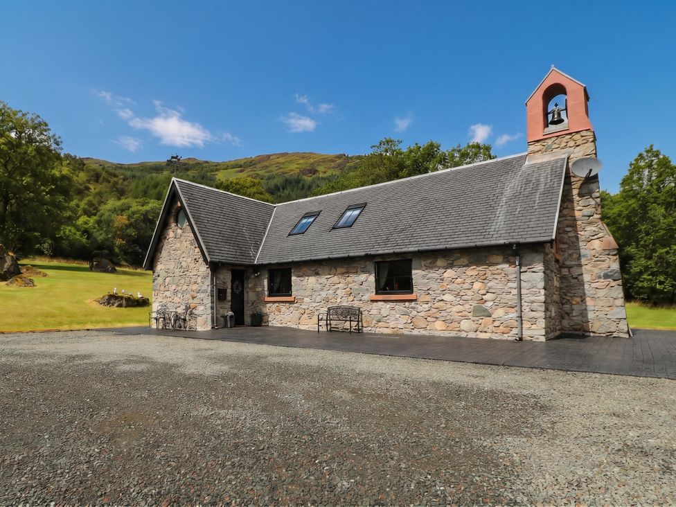 A stone building with a bell tower and bench at Ardlui Church in Inverarnan near Crianlarich
