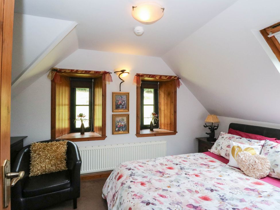 A bedroom featuring a bed, armchair and windows at Ardlui Church in Inverarnan near Crianlarich
