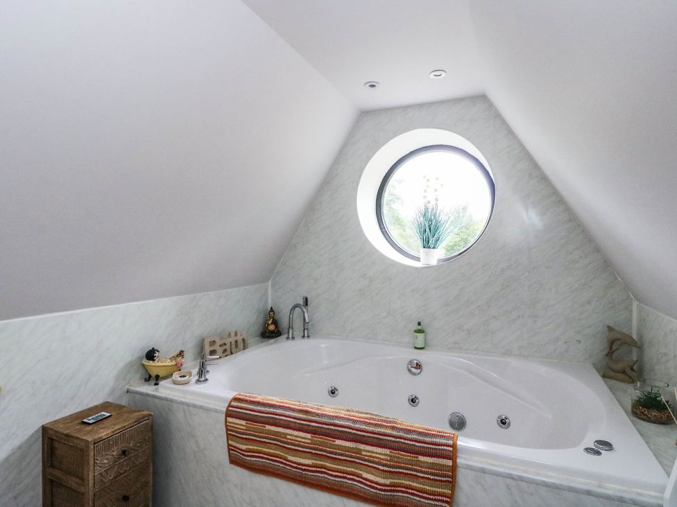 A bathroom with a large bathtub and round window at Ardlui Church Inverarnan near Crianlarich