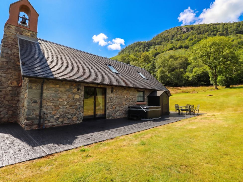 A stone building with a bell tower and outdoor seating at Ardlui Church in Inverarnan near Crianlarich