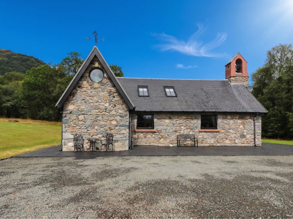 A stone house with outdoor seating at Ardlui Church Inverarnan near Crianlarich