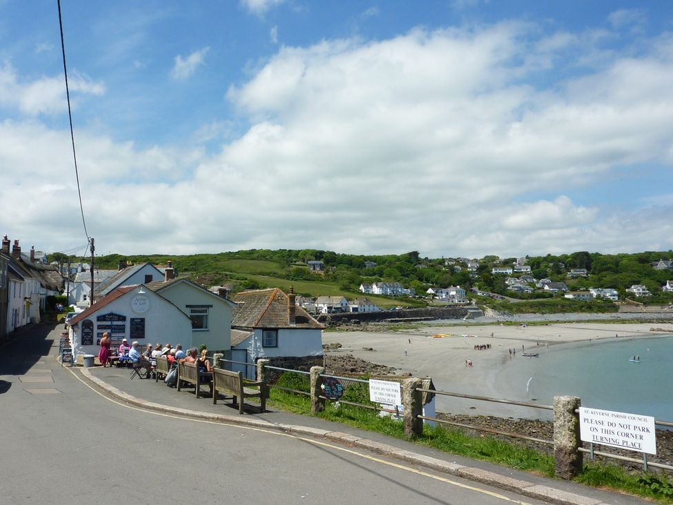 A beach with people and houses along the shore at The Mariners in Coverack
