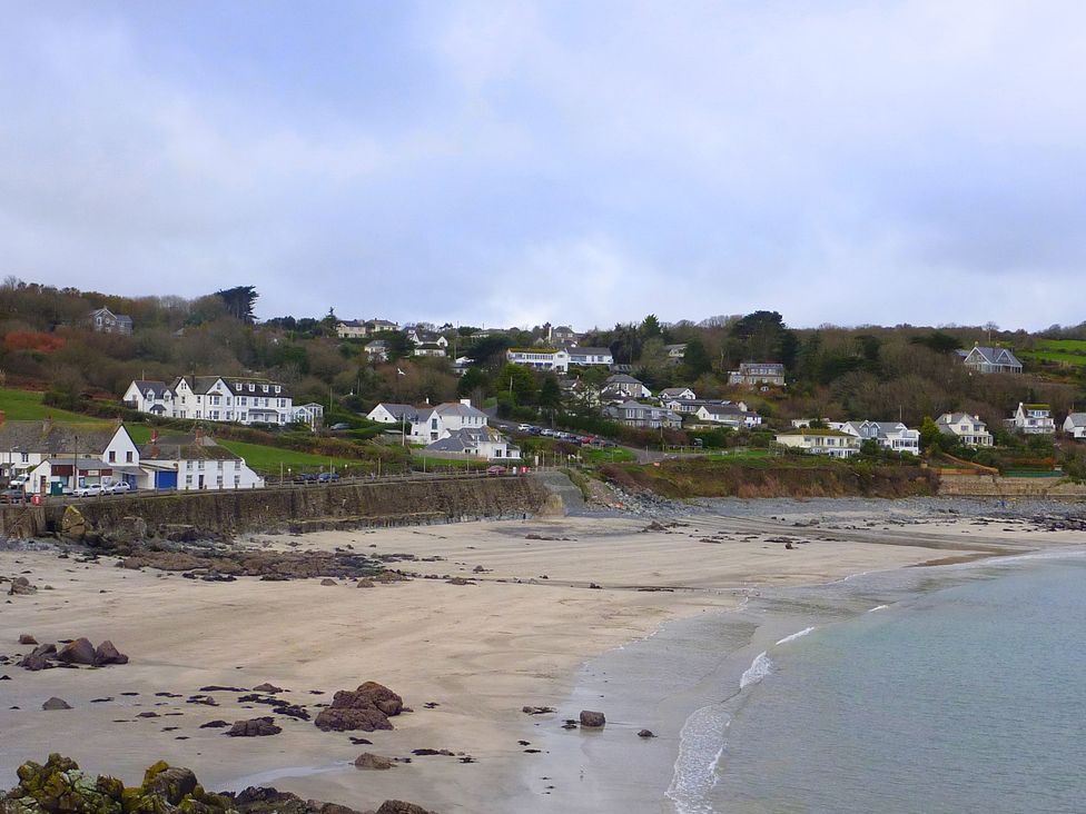 A beach with water and houses in the background at The Mariners in Coverack
