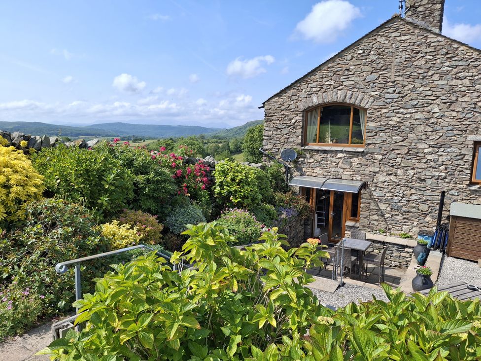 A garden with a stone house and seating area at Horse and Farrier Barn in Newton in Cartmel near Cartmel