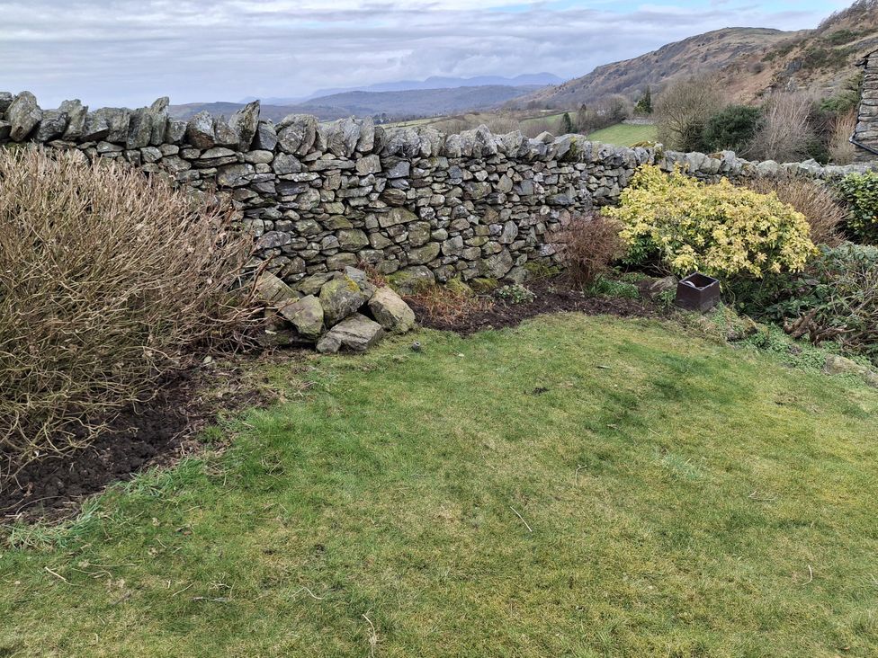 A garden with a stone wall and grassy area at Horse and Farrier Barn Newton in Cartmel near Cartmel