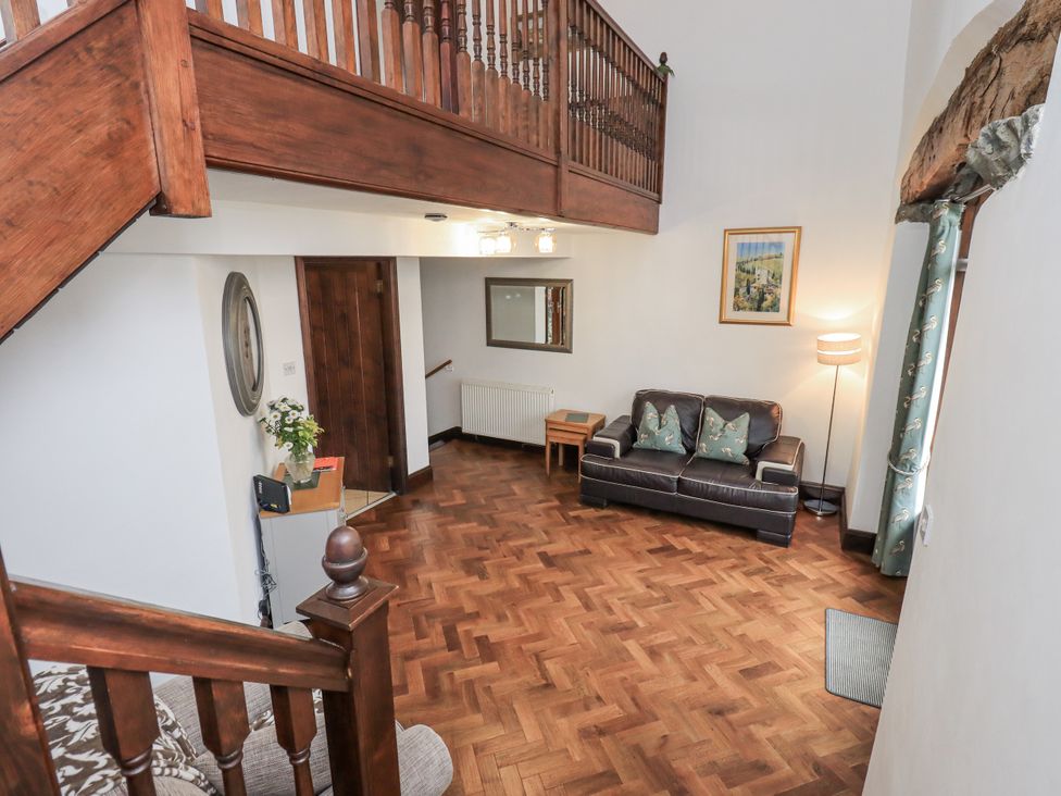 A living room with a sofa and staircase at Horse and Farrier Barn Newton in Cartmel near Cartmel
