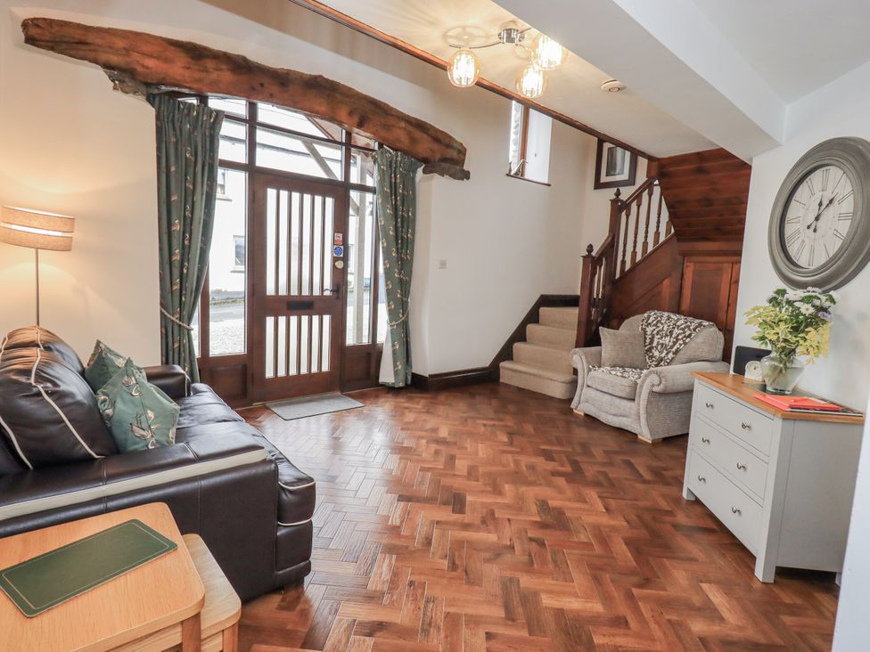 A living room with a sofa and armchair at Horse and Farrier Barn near Newton in Cartmel