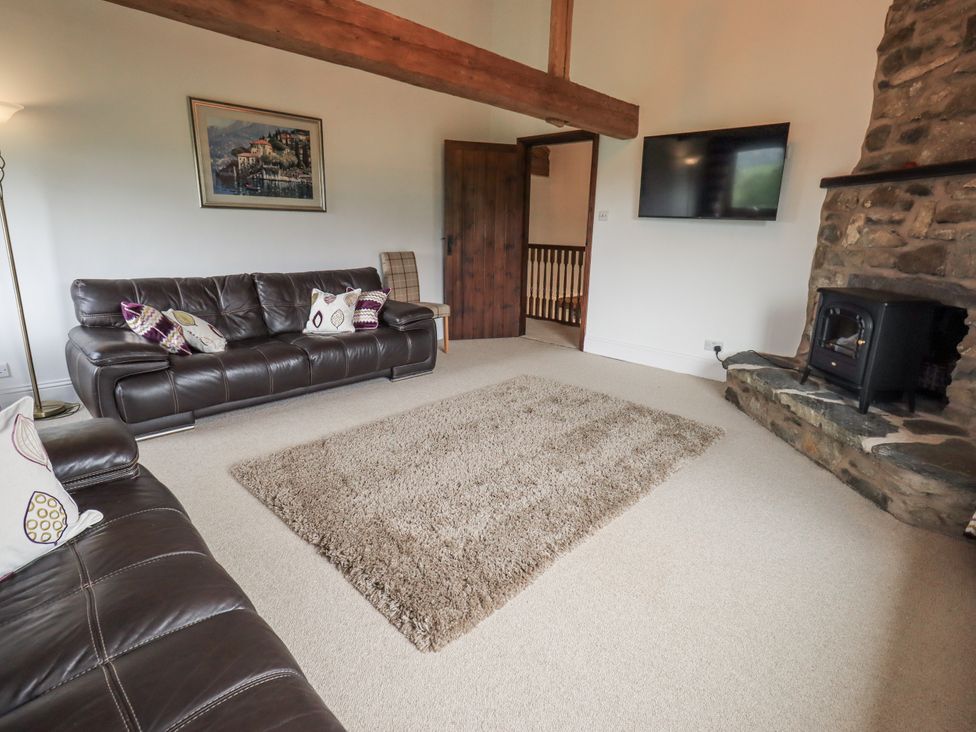 A living room with a sofa and a fireplace at Horse and Farrier Barn in Newton in Cartmel near Cartmel