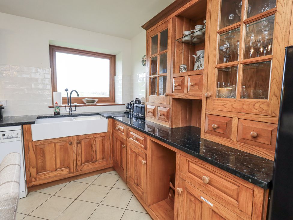 A kitchen with wood cabinets and a sink at Horse and Farrier Barn, Newton in Cartmel near Cartmel