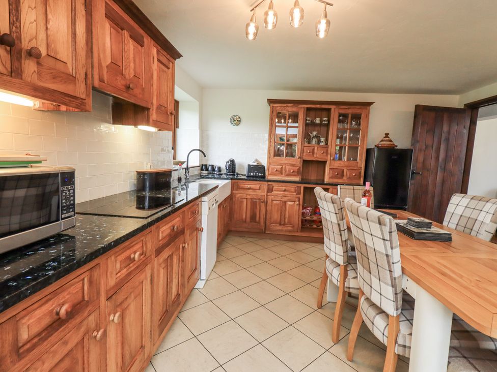 A kitchen with wooden cabinets and a dining table at Horse and Farrier Barn in Newton in Cartmel near Cartmel
