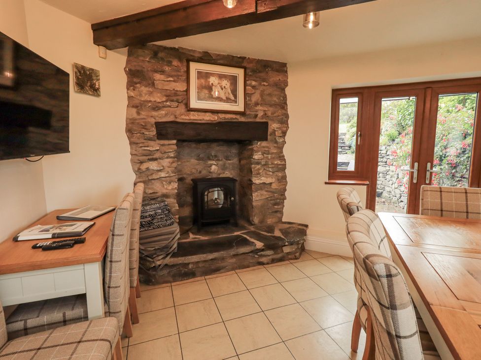 A dining room with a fireplace and windows at Horse and Farrier Barn in Newton in Cartmel near Cartmel