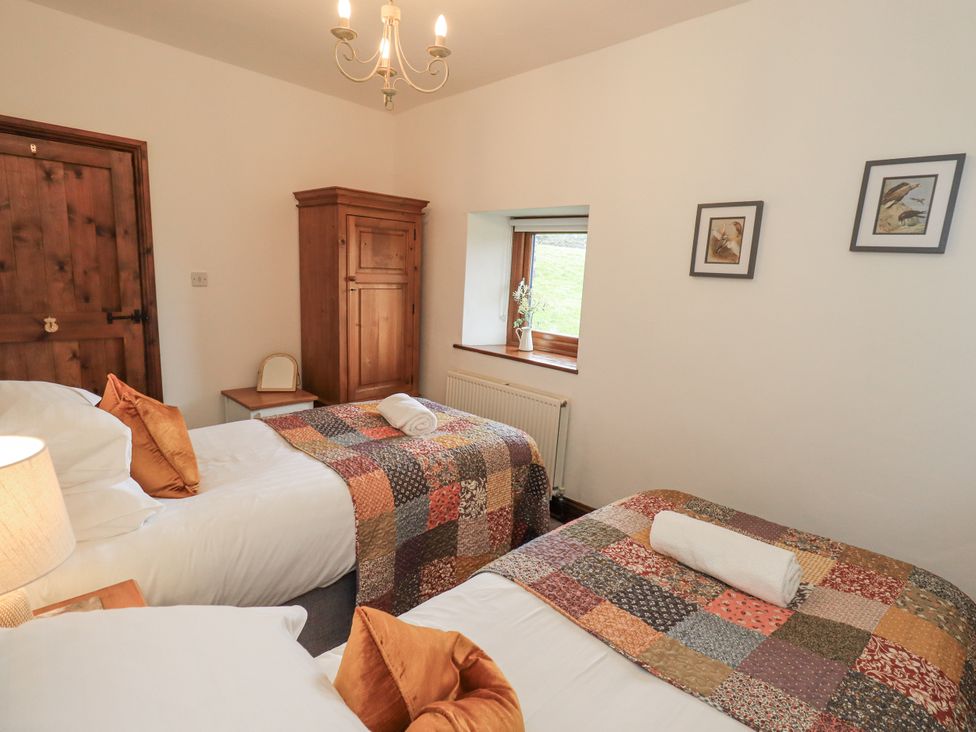 A bedroom with two beds and a wardrobe at Horse and Farrier Barn in Newton in Cartmel near Cartmel