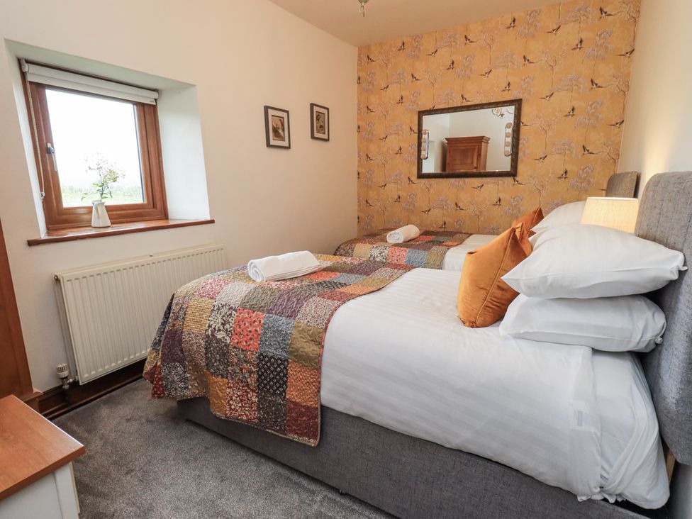 A bedroom with two beds and a window at Horse and Farrier Barn Newton in Cartmel near Cartmel