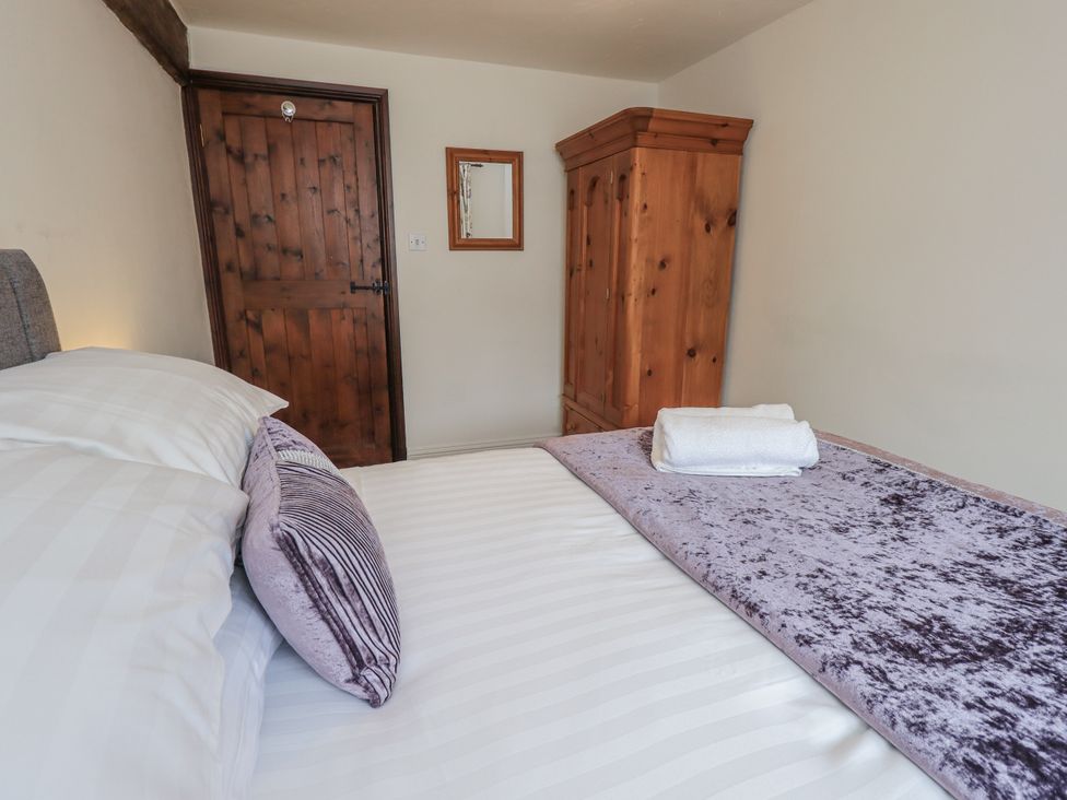 A bedroom with a bed and wooden wardrobe at Horse and Farrier Barn Newton in Cartmel near Cartmel