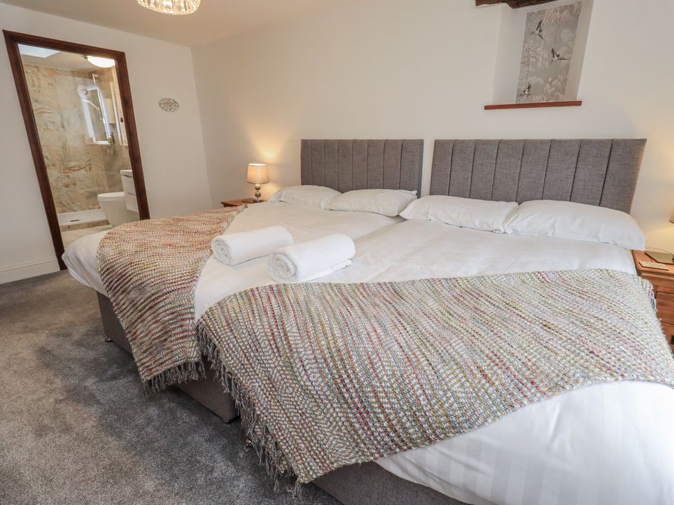 A bedroom with two beds and an ensuite bathroom at Horse and Farrier Barn in Newton in Cartmel near Cartmel