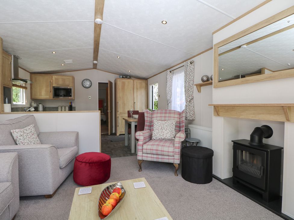 A living room with seating, coffee table and kitchen area at 18 Deer Glade in Landford