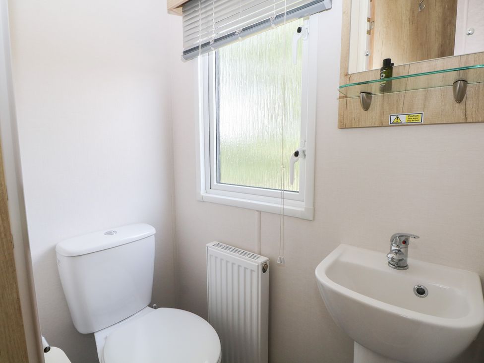 A bathroom with a toilet, sink, and window at 18 Deer Glade in Landford