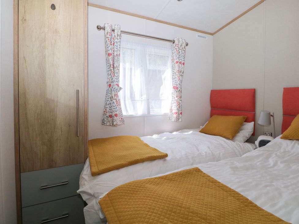 A bedroom with two beds and a wardrobe at 18 Deer Glade in Landford