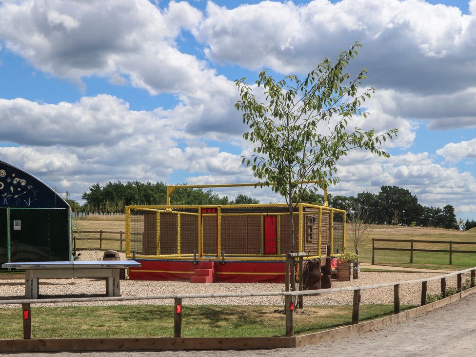 An outdoor play area with a play structure and tree at 18 Deer Glade in Landford