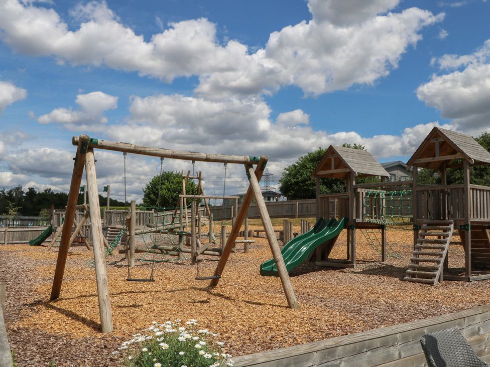 A playground with swings and a climbing frame at 18 Deer Glade in Landford