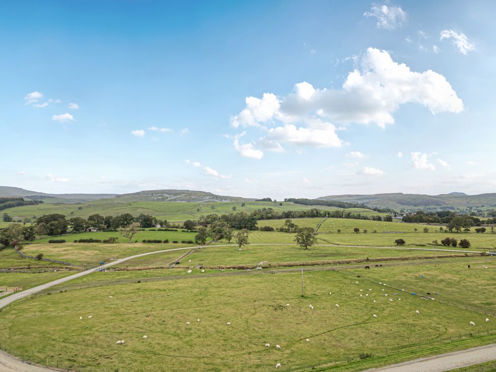 A view of fields with sheep and trees at Orcaber Farmhouse in Austwick