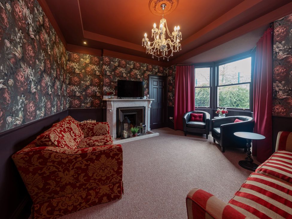 A living room with a sofa, armchairs, a television, and a fireplace at Wonderland in Tweedmouth, Berwick-Upon-Tweed