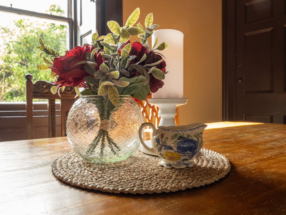 A table with flowers in a vase and a cup at Wonderland in Tweedmouth, Berwick-Upon-Tweed