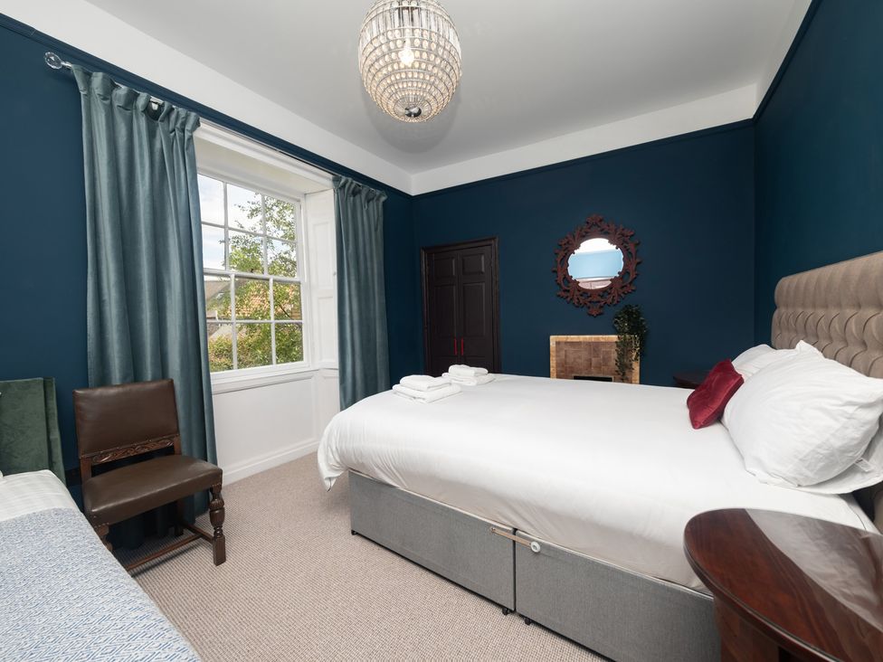 A bedroom with a bed and chair at Wonderland, Tweedmouth, Berwick-Upon-Tweed
