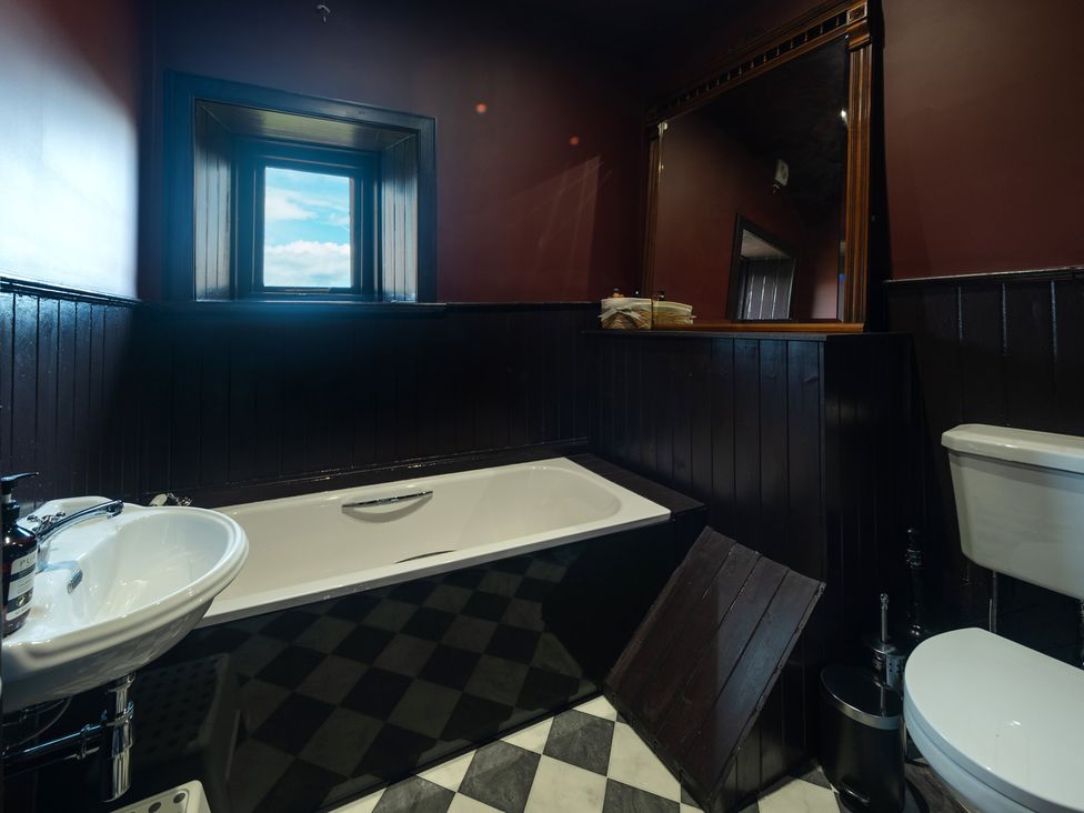 A bathroom with a bathtub, sink, toilet, and mirror at Wonderland in Tweedmouth, Berwick-Upon-Tweed