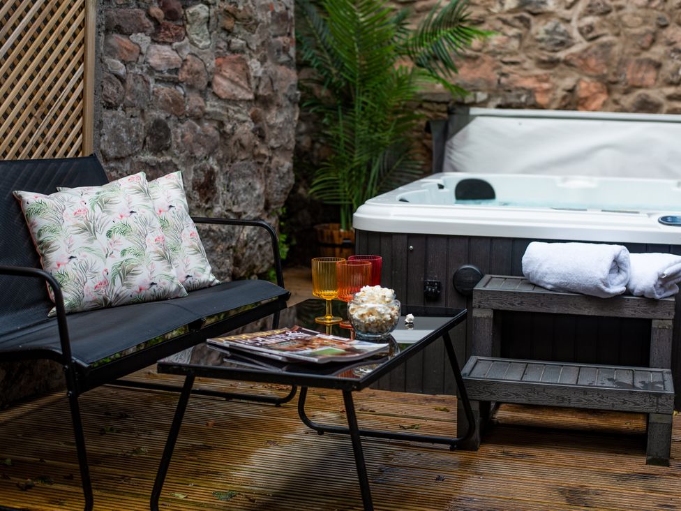 An outdoor area with a hot tub, sofa, and table at Wonderland in Tweedmouth, Berwick-Upon-Tweed