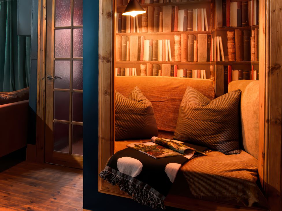 A reading nook with a sofa and bookshelf at Wonderland, Tweedmouth, Berwick-Upon-Tweed