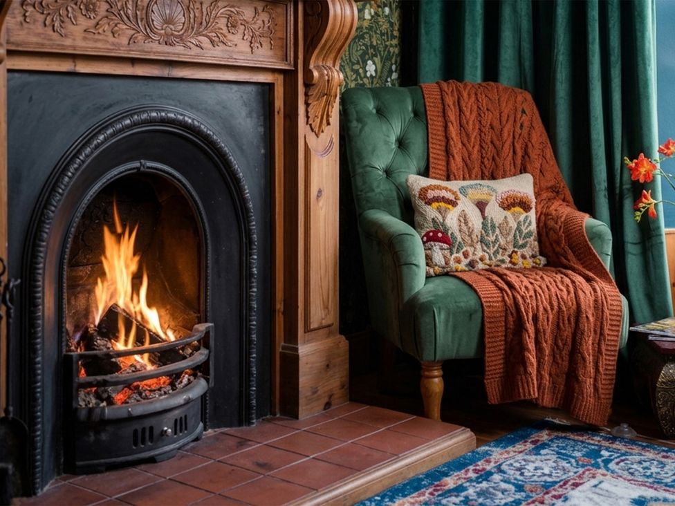A living room with a fireplace and a green armchair at Wonderland in Tweedmouth, Berwick-Upon-Tweed