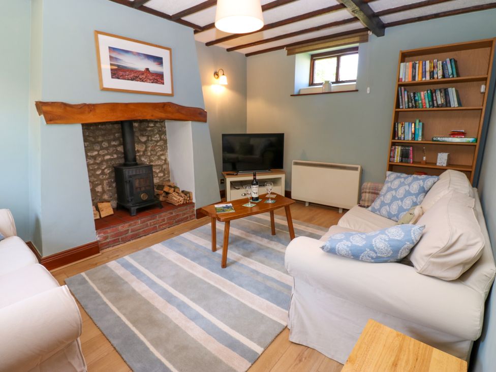 A living room with a wood stove, sofa, and bookshelf at Mordon Moor Cottage Sedgefield, County Durham
