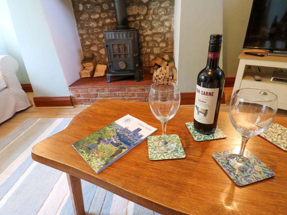 A living room with a fireplace and wine on the table at Mordon Moor Cottage in Sedgefield, County Durham