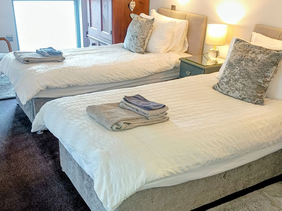 A bedroom with two beds and a bedside table at The Dairy at Brackenthwaite Farm in Arnside