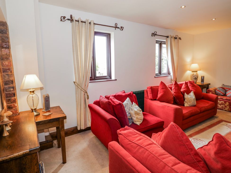 A living room with red sofas and a lamp at The Haybarn in Lichfield