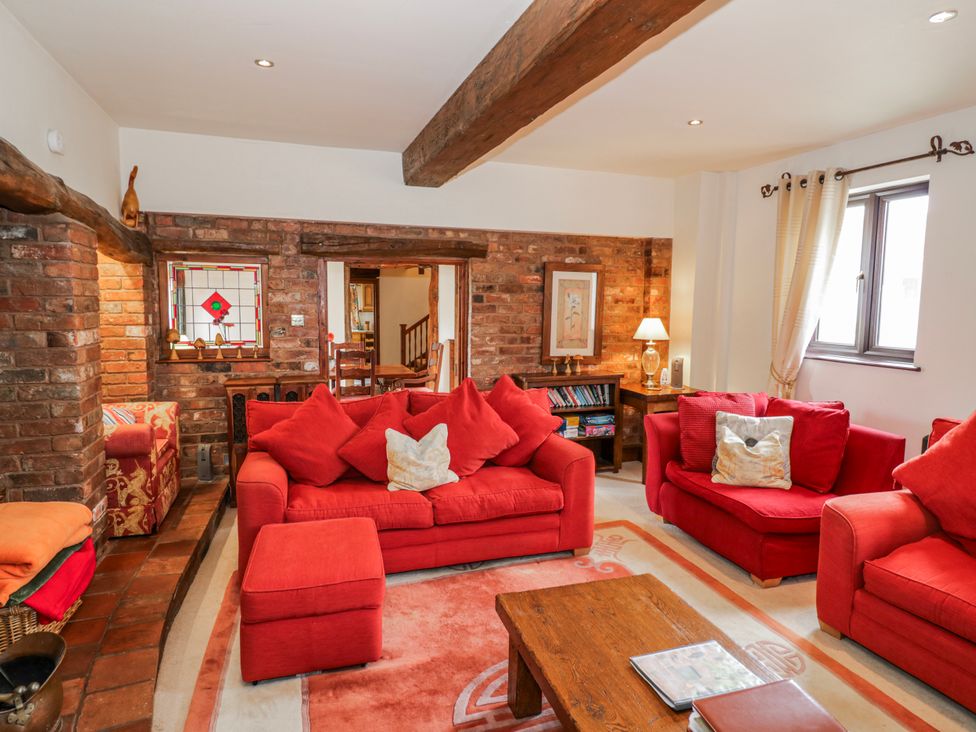 A living room with red sofas and a coffee table at The Haybarn in Lichfield