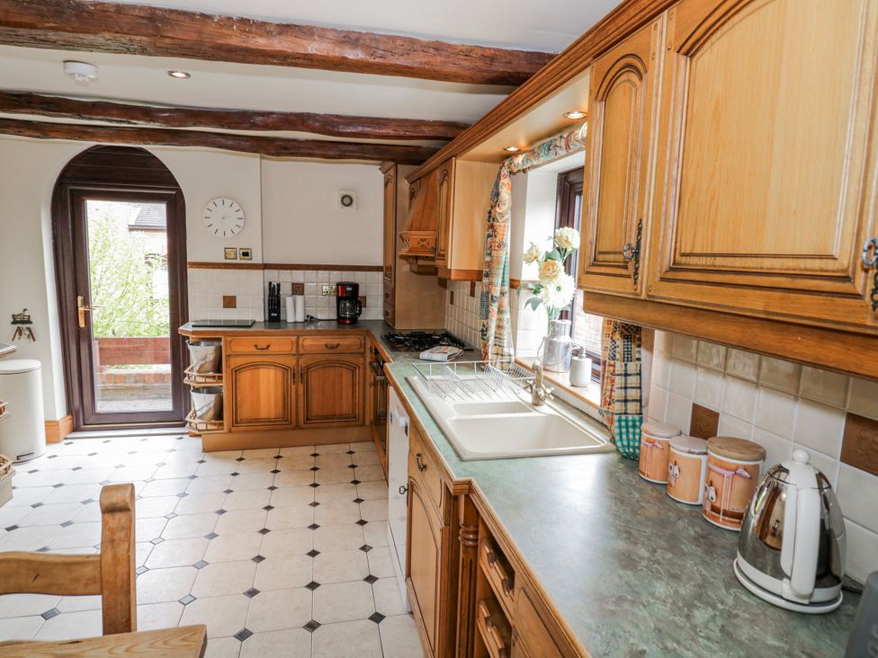 A kitchen with wooden cabinets and a sink at The Haybarn in Lichfield