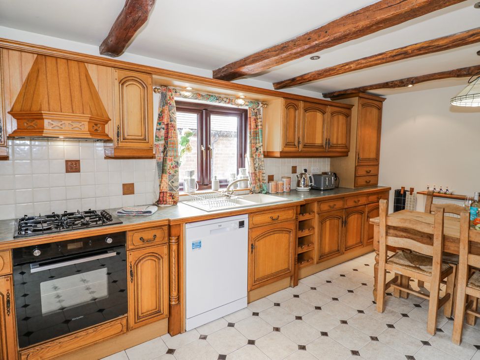 A kitchen with wooden cabinets and appliances at The Haybarn in Lichfield