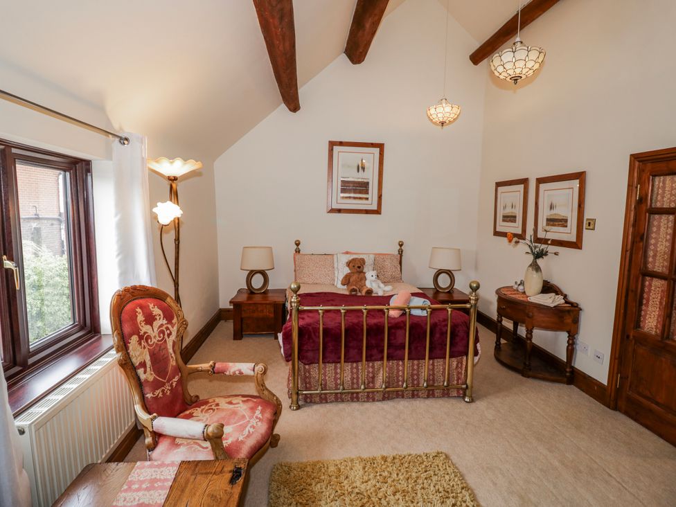 A bedroom with a bed and armchair at The Haybarn in Lichfield