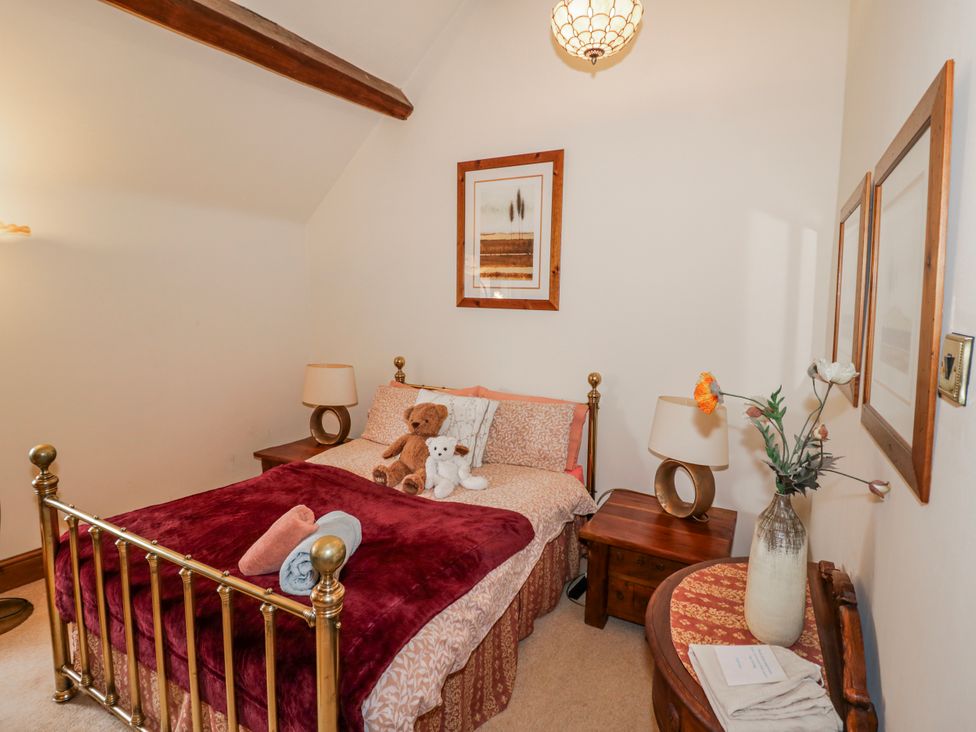 A bedroom with a brass bed frame and teddy bears at The Haybarn in Lichfield