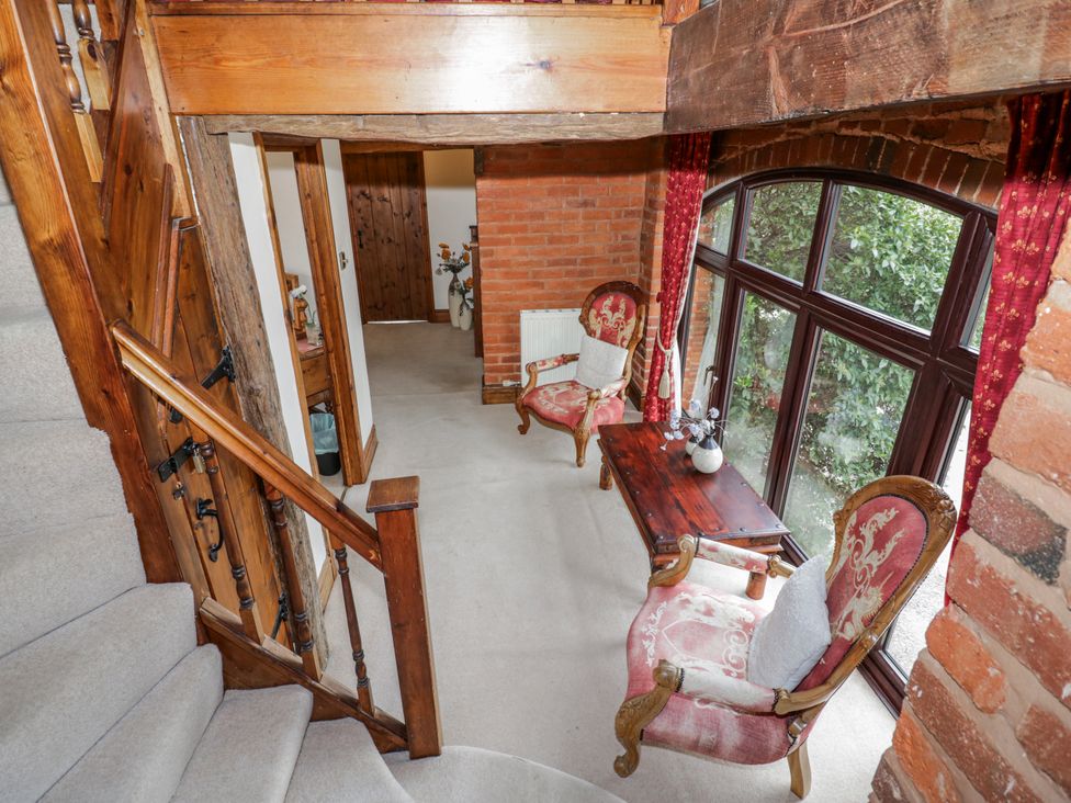 A hallway with a staircase and seating area at The Haybarn in Lichfield
