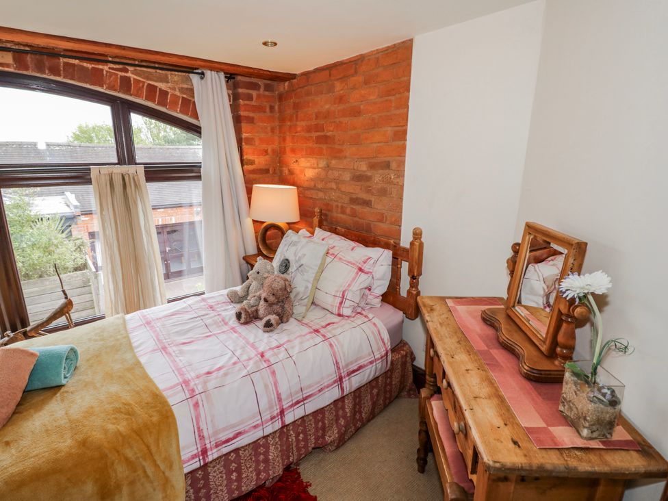 A bedroom with a bed and a wooden table at The Haybarn in Lichfield