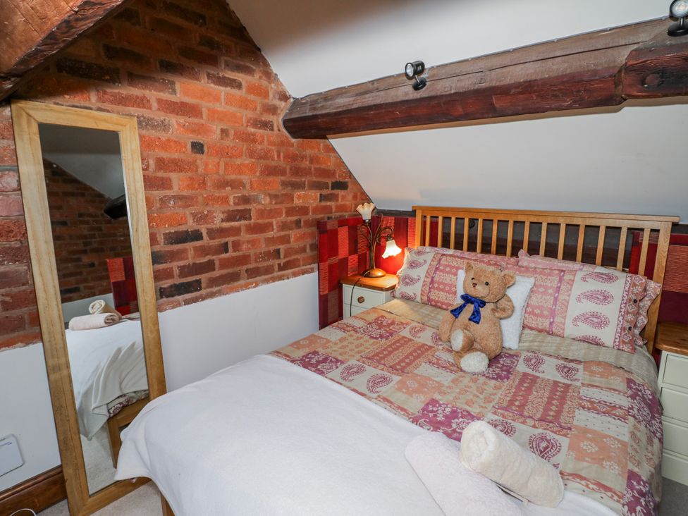 A bedroom with a bed and mirror at The Haybarn in Lichfield