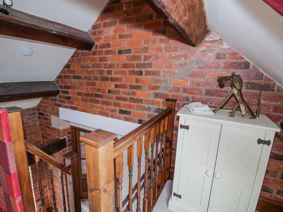 A staircase with wooden railing and a cabinet at The Haybarn in Lichfield