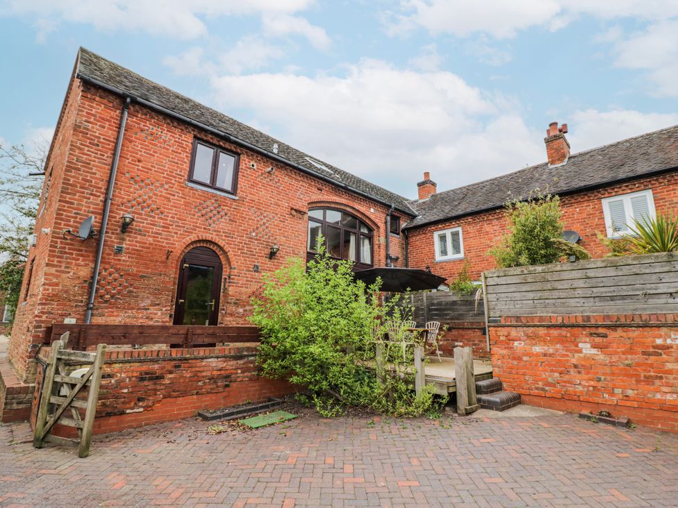 A brick house with a garden and patio furniture at The Haybarn in Lichfield