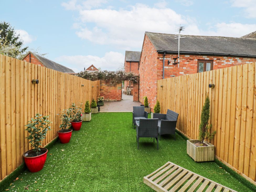 A garden with artificial grass and seating area at The Haybarn in Lichfield