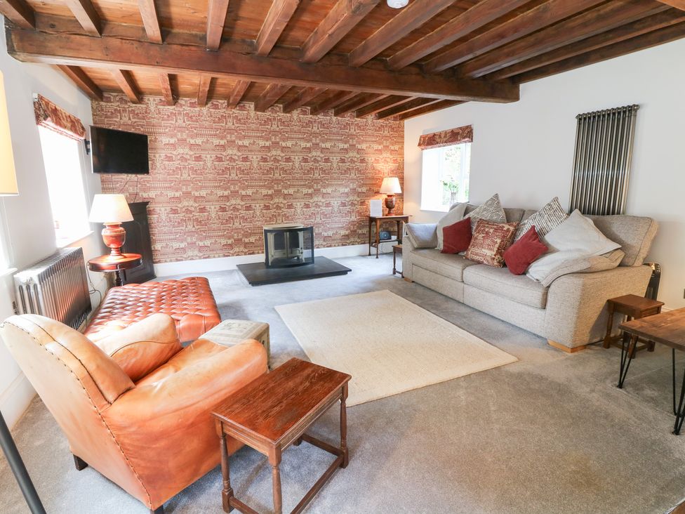 A living room with a sofa, armchair, and coffee table at The Old Barn in Caenby near Market Rasen